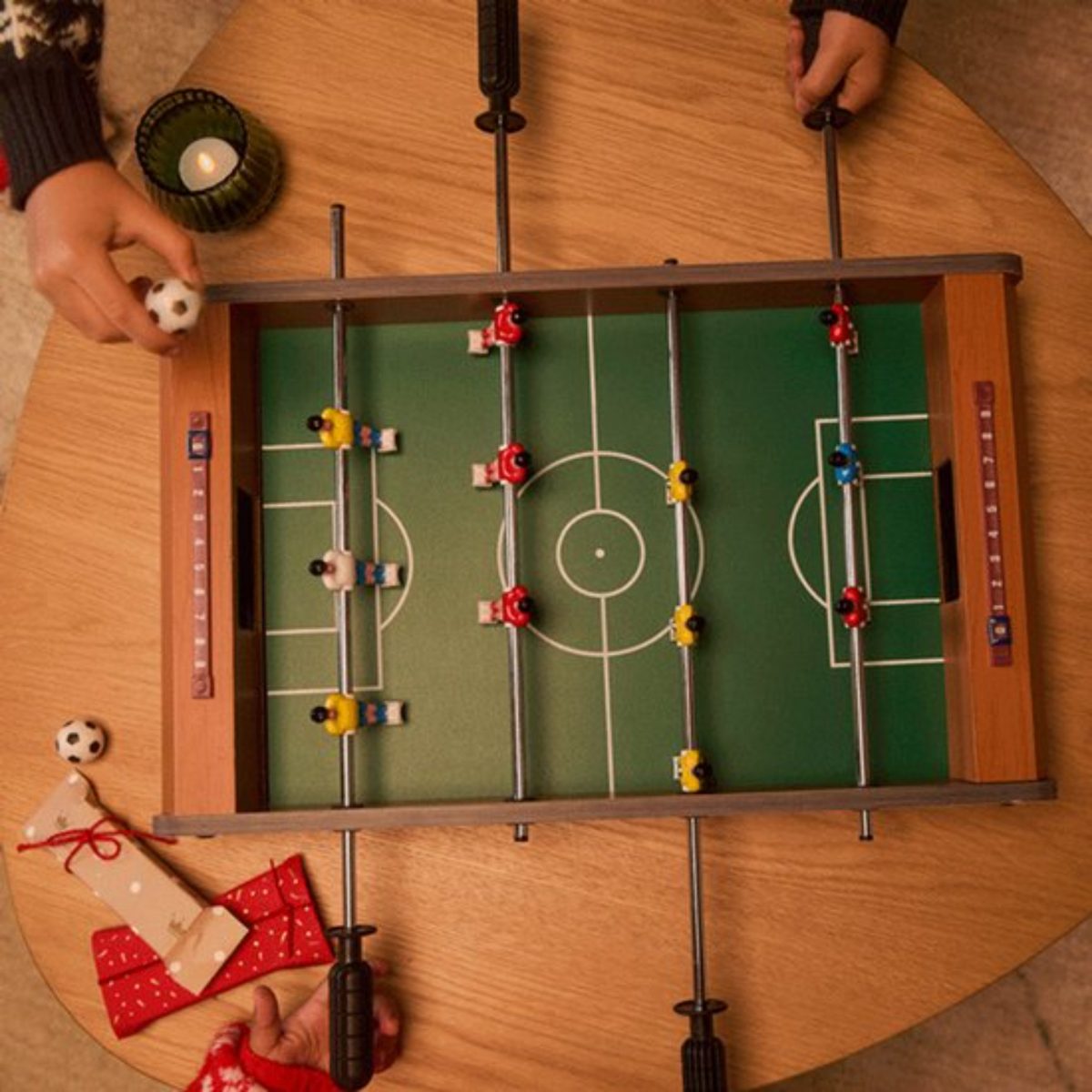 Lupilu Mini Calcio Balilla appoggiato su tavolo con bambini che giocano e regali natalizi