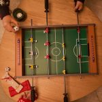 Lupilu Mini Calcio Balilla appoggiato su tavolo con bambini che giocano e regali natalizi