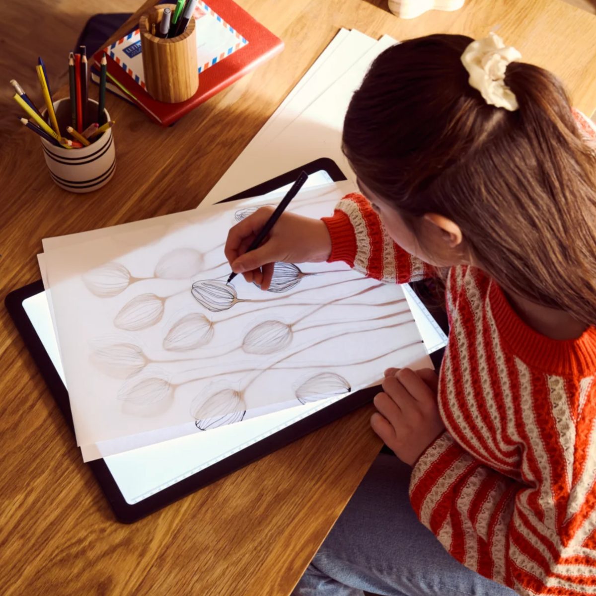 Bambina disegna fiori su carta appoggiata alla Tavoletta Luminosa LED Crelando A4