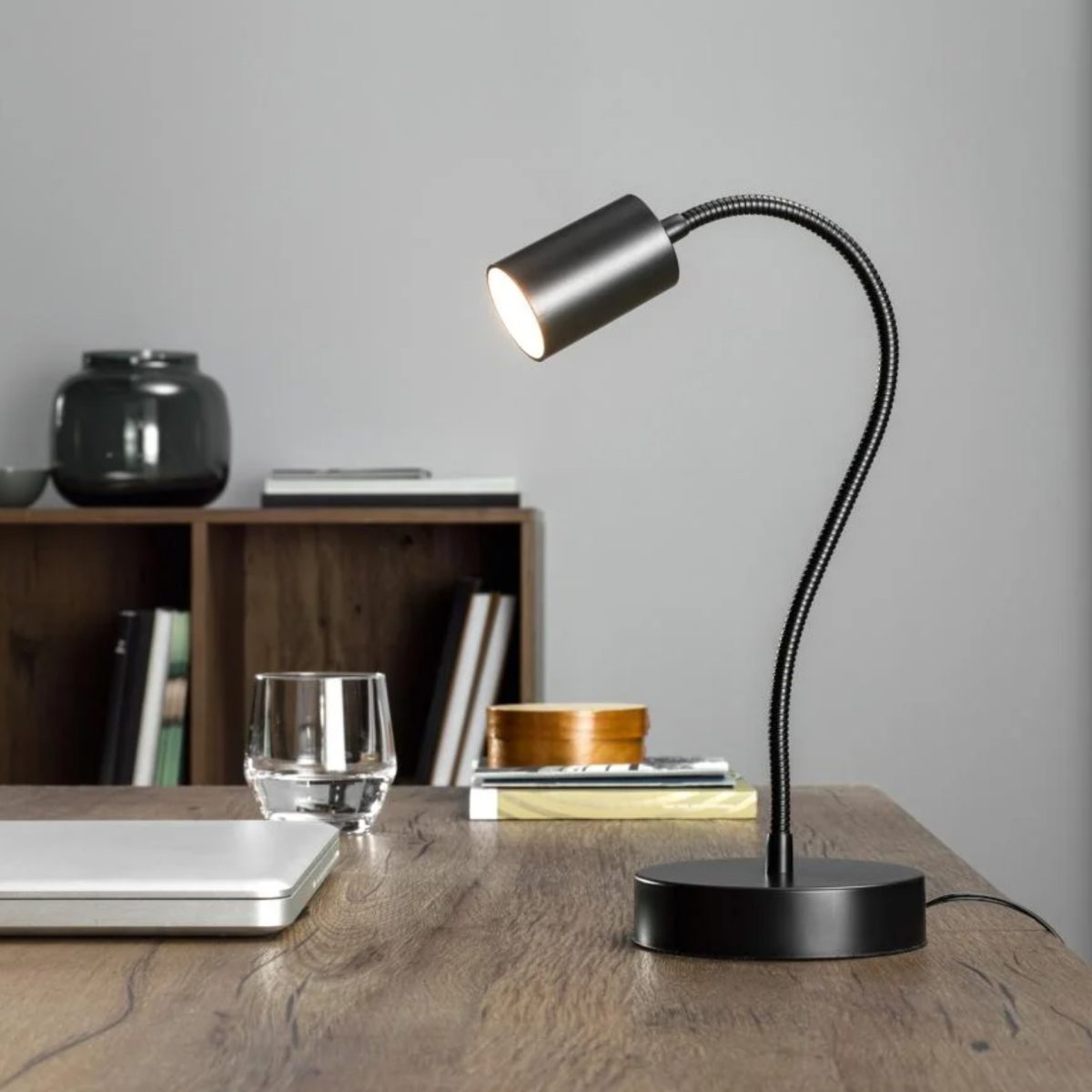 Lampada LED Livarno Home con base nera e braccio flessibile accesa su scrivania in legno, ambientazione da studio