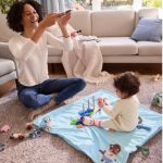 Bambina gioca sulla coperta Lupilu con giochi ad incastro in legno e sonagli inclusi