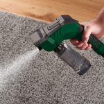 Spazzola Parkside Wet Dry in uso su tappeto grigio, spruzzo acqua dal serbatoio 350ml