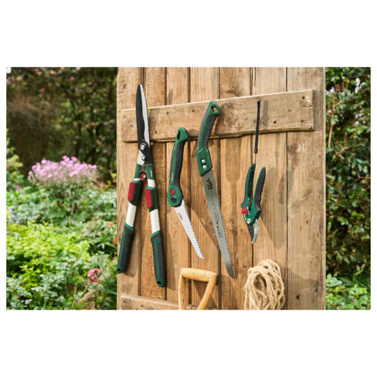 Segaccio Parkside appeso insieme a cesoie e forbici da giardino su parete in legno