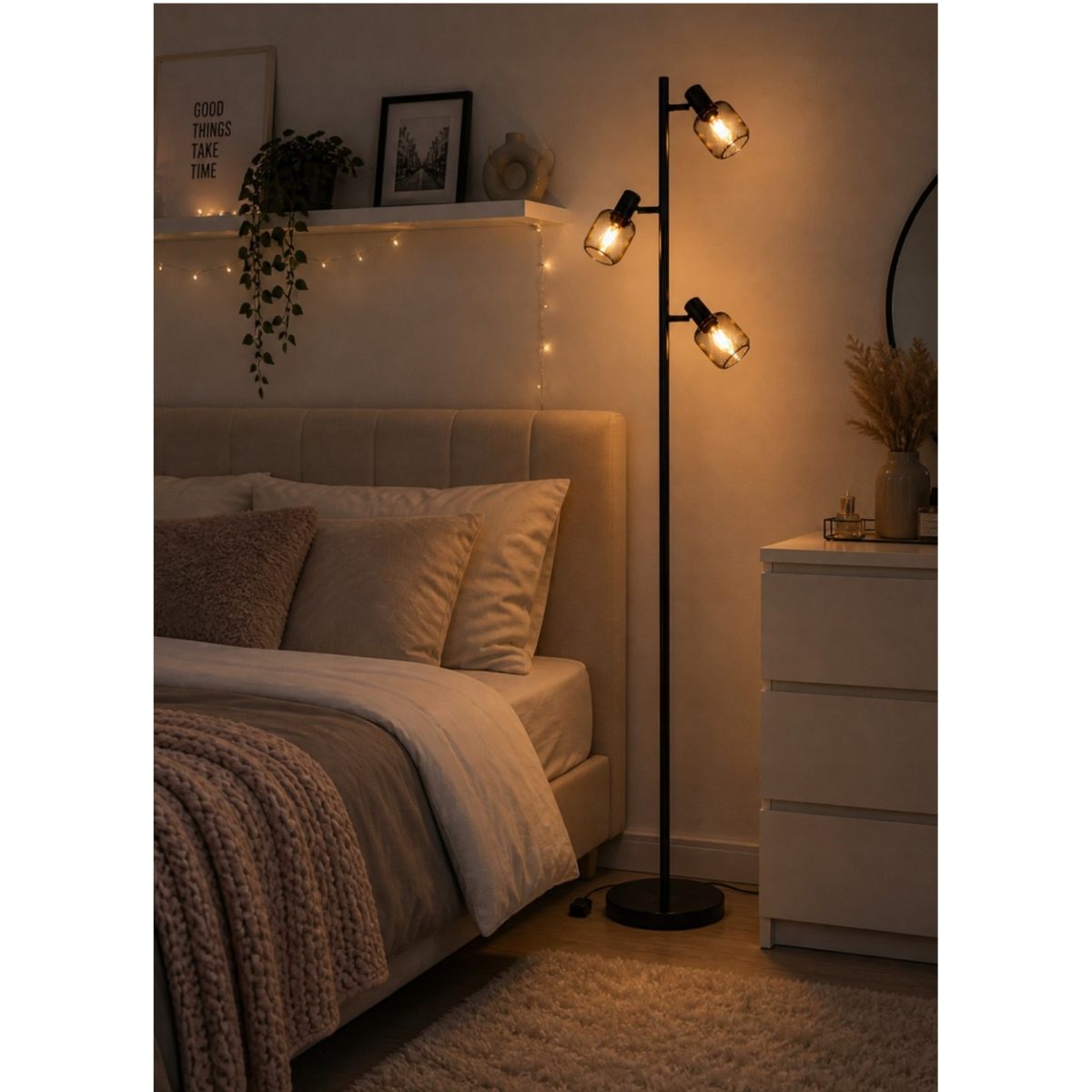 Lampada da terra Livarno Loft nera accesa in camera da letto accanto a comò bianco, luce calda soffusa