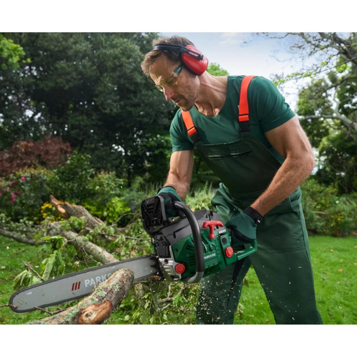 Uomo utilizza la motosega Parkside PBKS 53 per tagliare rami in giardino con protezioni di sicurezza