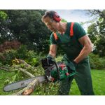 Uomo utilizza la motosega Parkside PBKS 53 per tagliare rami in giardino con protezioni di sicurezza