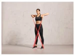 Donna allena braccia con fascia elastica rossa Crivit incrociata sotto i piedi durante allenamento