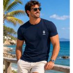 T-shirt Esmara uomo blu navy indossata da modello in ambientazione estiva al mare con palme